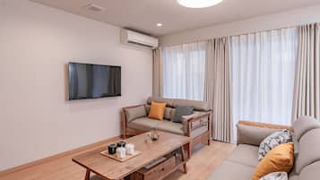 A modern living room with a sofa, a coffee table, and a flat-screen TV mounted on the wall.