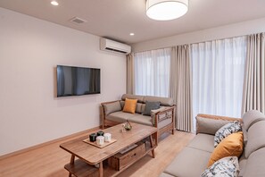 Una sala de estar moderna con un sofá, una mesa de centro y un televisor de pantalla plana montado en la pared.