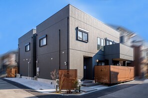 A modern hotel with a flat facade, multiple windows, and a wooden entrance.