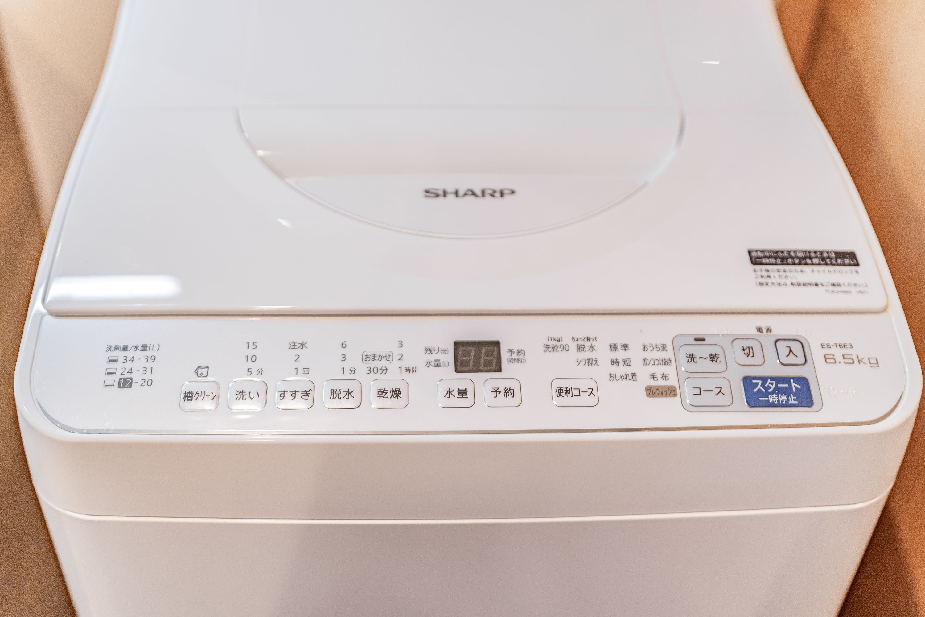 A white Sharp washing machine with Japanese labels, a digital display, and various control buttons.