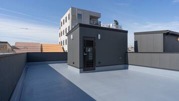 A rooftop terrace with a small building, a door, and a window.