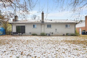A two-story house with a brick exterior, a covered porch, and a snow-covered yard.