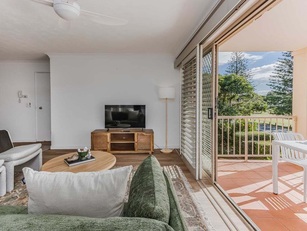 A modern living room with a flat-screen TV, a wooden coffee table, and a sofa.