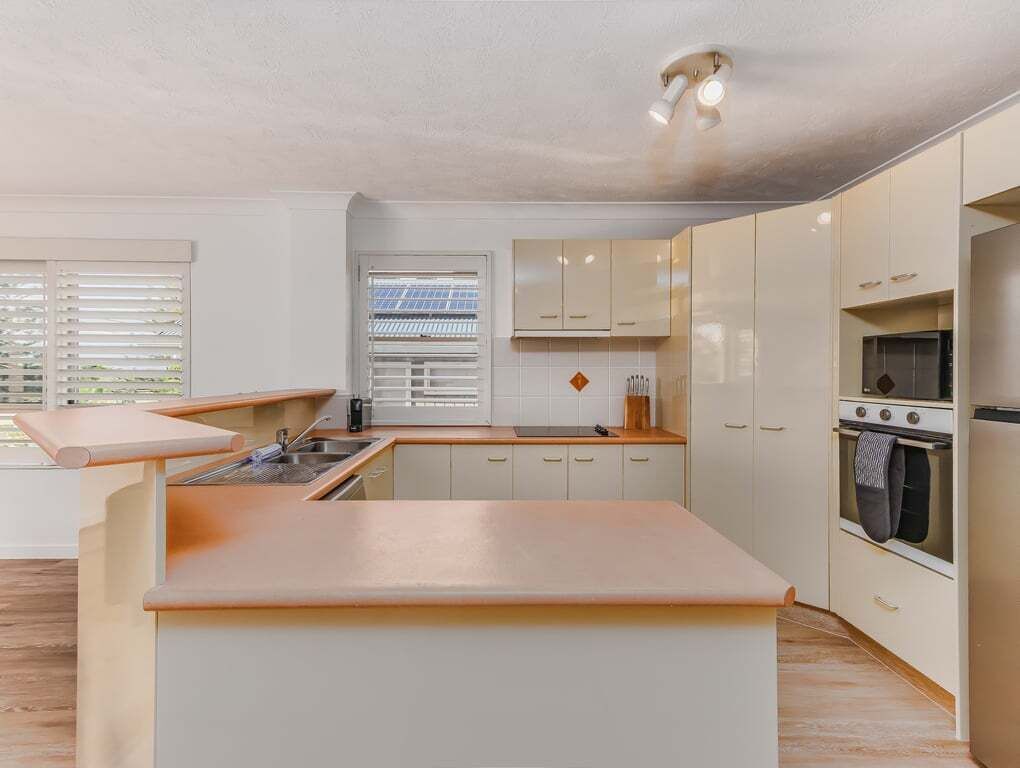 Una cucina moderna con isola centrale, mobili bianchi e forno integrato.