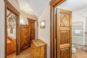 A hallway with wooden doors, a small wooden bench, and a tiled bathroom with a toilet and towel rack. - Courmayeur Apartment X6 Parking, Courmayeur, Italy (Courmayeur)