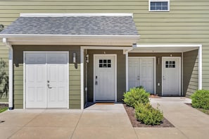 Un immeuble résidentiel doté d’une entrée de garage, d’une porte d’entrée et d’un petit espace porche.