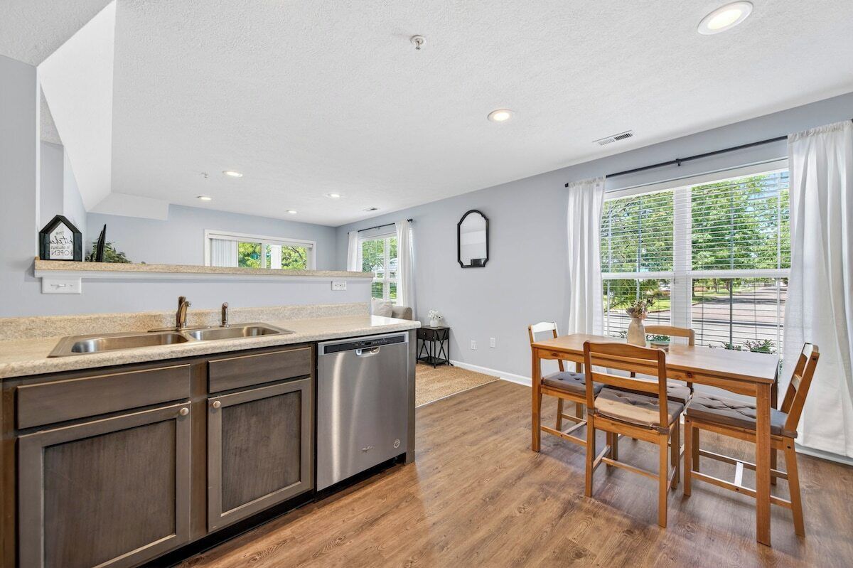A kitchen with a dishwasher, a sink, and a dining area with a table and chairs.