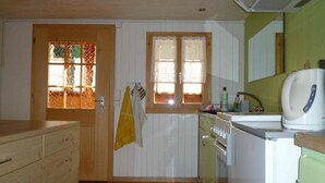 A compact kitchen with wooden cabinets, a stove, and a sink. - Auf der Mauer Appartement/Fewo, Dusche oder Bad, WC, 2 Schlafräume by Interhome (Oberwil)