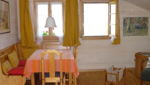 A cozy dining area with a table set for four, wooden chairs, a bench with cushions, and a hanging lamp. - Auf der Mauer Appartement/Fewo, Dusche oder Bad, WC, 2 Schlafräume by Interhome (Oberwil)