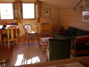 A cozy living room with a wooden floor, a green sofa, a wicker chair, a wooden table, and a laptop on a desk. - Auf der Mauer Appartement/Fewo, Dusche oder Bad, WC, 2 Schlafräume by Interhome (Oberwil)
