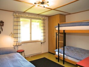 A dormitory room with bunk beds, a radiator, a window with curtains, and a ceiling fan. - Pony 5-Bettwohnung Appartement/Fewo, Dusche oder Bad, WC, 2 Schlafräume by Interhome (Lenk)