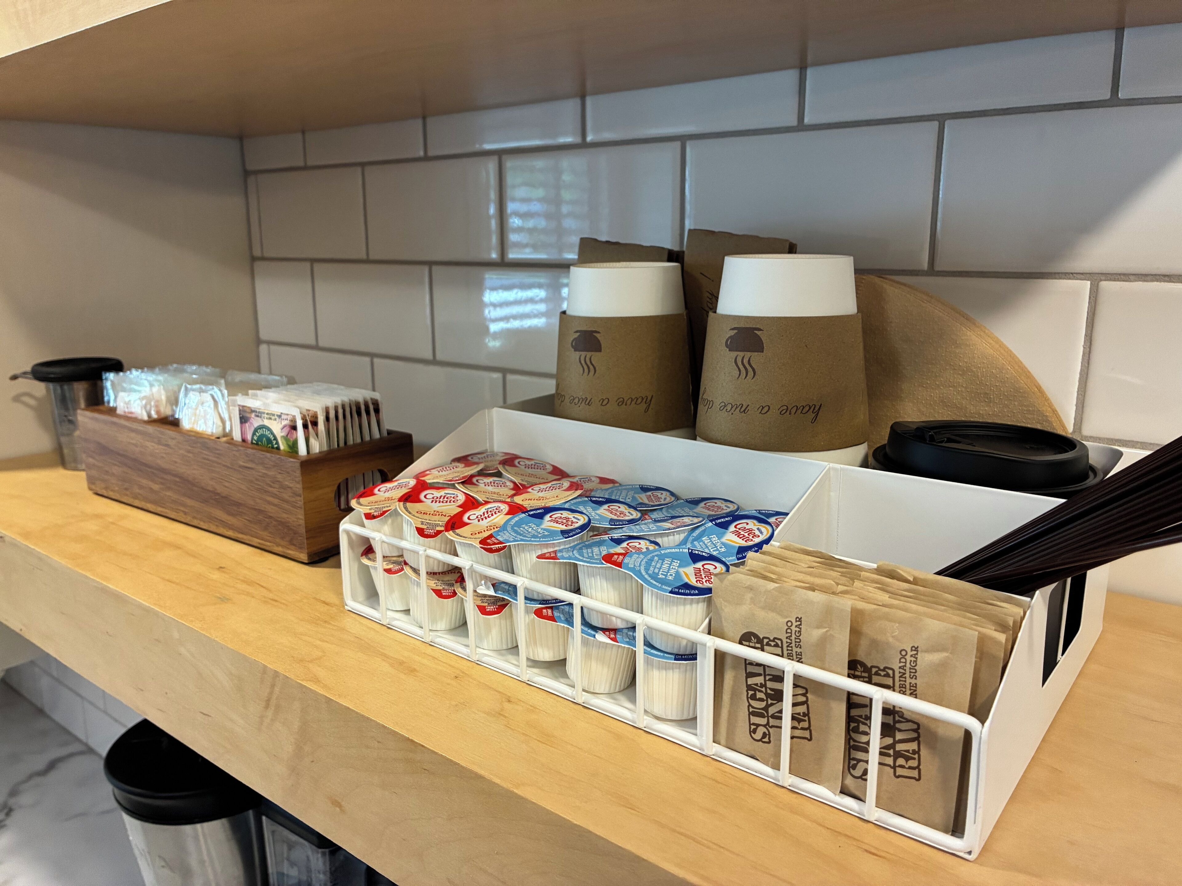 A kitchen counter with coffee pods, sugar packets, and paper bags.