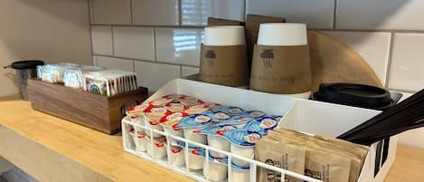 Una encimera de cocina con cápsulas de café, sobres de azúcar y bolsas de papel.