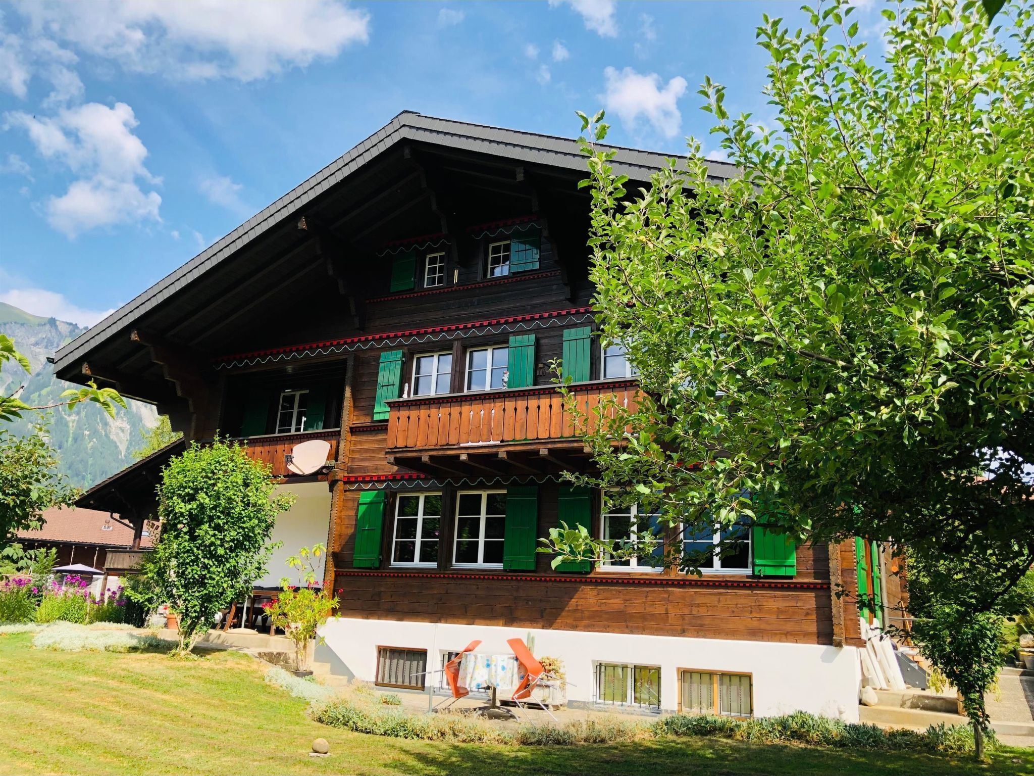 Un immeuble à plusieurs étages, doté d’un toit en pente, de balcons en bois et de volets verts.