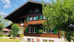 A multi-story building with a sloped roof, wooden balconies, and green shutters. - Träumli Appartement/Fewo, Dusche oder Bad, WC, 1 Schlafraum 2-Bett-Wohnung by Interhome (Lenk)