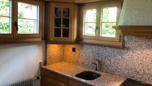 A kitchen with granite countertops, wooden cabinets, and a built-in sink. - Träumli Appartement/Fewo, Dusche oder Bad, WC, 1 Schlafraum 2-Bett-Wohnung by Interhome (Lenk)