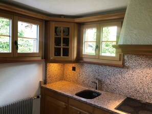 Eine Küche mit Granit Arbeitsplatten, Holzschränken und einer eingebauten Spüle.