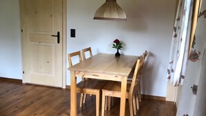 A wooden dining table with chairs, a vase with flowers, a hanging light fixture, and a door. - Träumli Appartement/Fewo, Dusche oder Bad, WC, 1 Schlafraum 2-Bett-Wohnung by Interhome (Lenk)