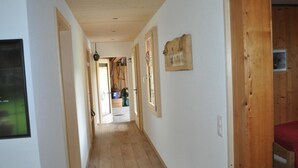 A hallway with wooden floors and walls, leading to a room with a bed. - Andrea Appartement/Fewo, Dusche oder Bad, WC, 3 Schlafräume 4-Zimmerhaus by Interhome (Lenk)