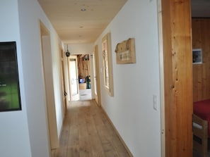 Ein Korridor mit Holzböden und -wänden, der zu einem Zimmer mit einem Bett führt.