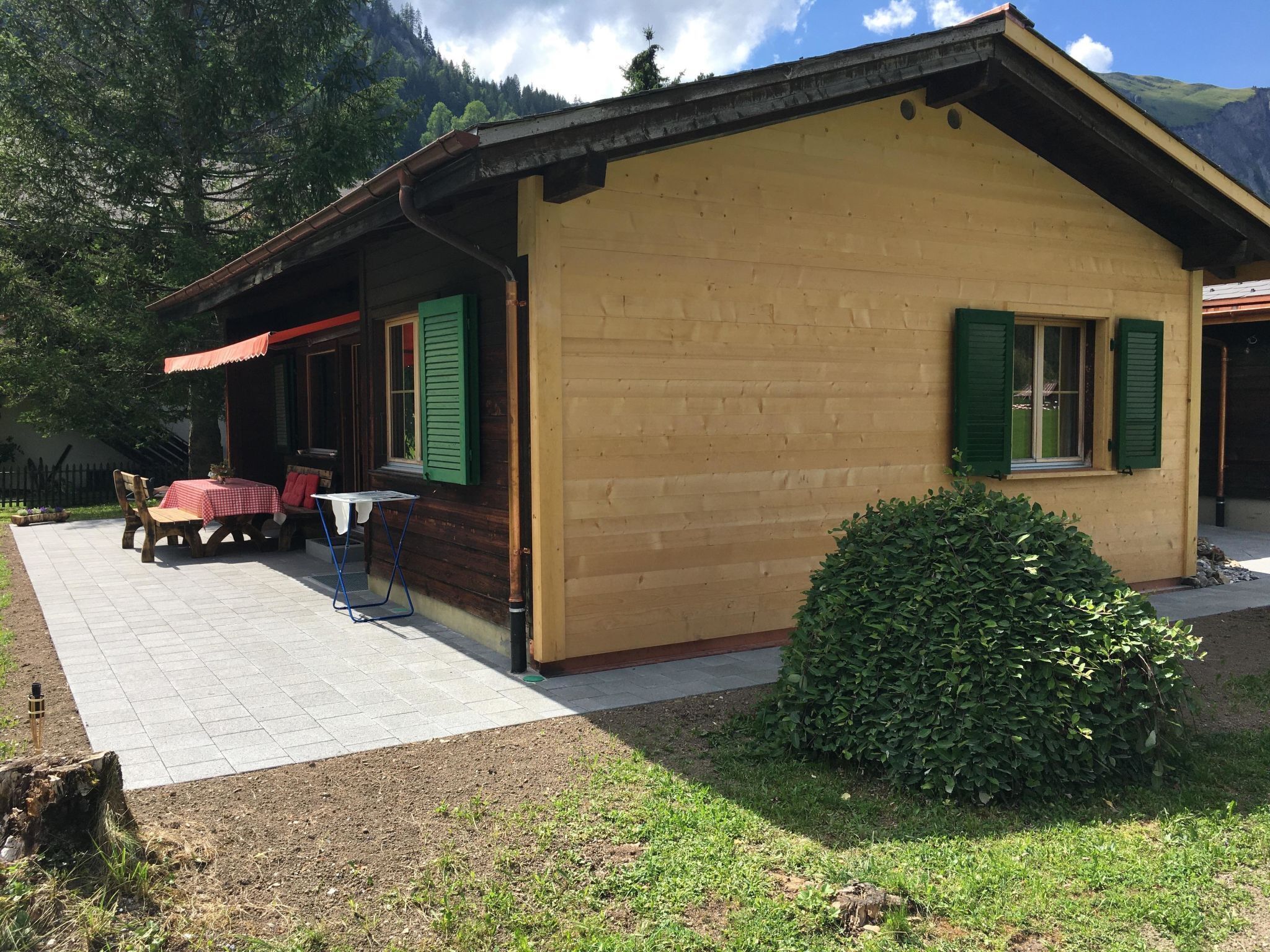 Een houten huis met een veranda, een tafel en stoelen ervoor.