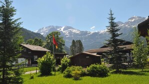 A rural setting with traditional wooden houses, a flag, and a mountain backdrop. - Andrea Appartement/Fewo, Dusche oder Bad, WC, 3 Schlafräume 4-Zimmerhaus by Interhome (Lenk)