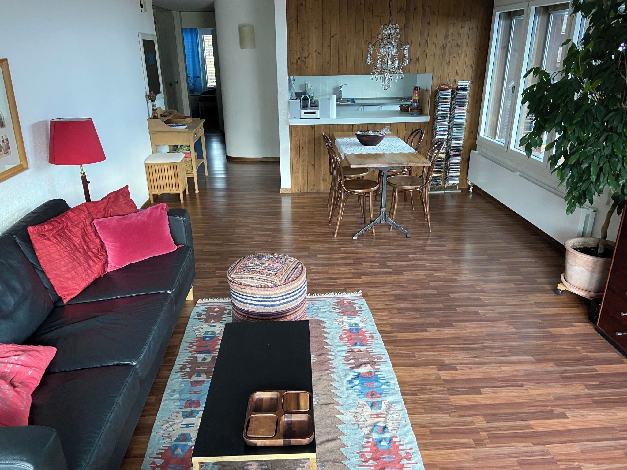 A modern living room with a black leather sofa, a coffee table, and a patterned rug.
