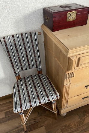 Ein Stuhl mit Streifenmuster und eine Holzkassette mit Schubladen.