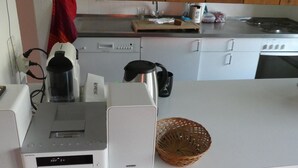 Cuina amb taulell blanc, cafetera, bullidor i cistella.