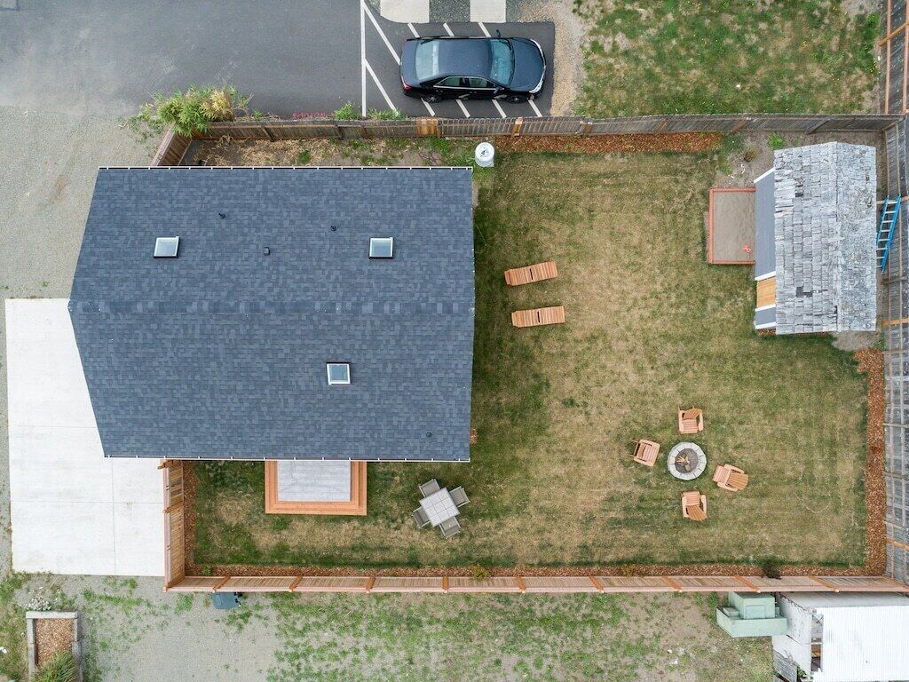 Eine Dachterrasse mit überdachter Terrasse, ein Auto auf der Auffahrt und ein kleiner Garten.