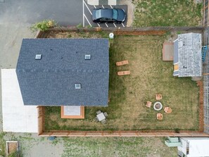 A rooftop with a covered patio area, a car parked in the driveway, and a small garden.