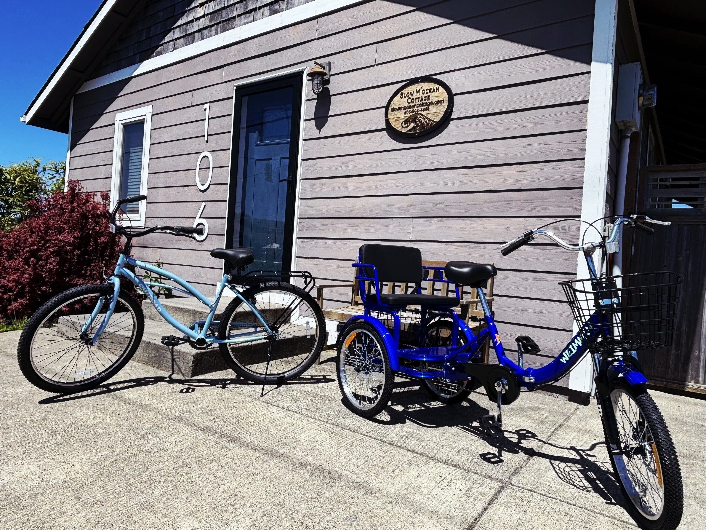 Une maison à deux étages avec un vélo bleu et un tricycle garés devant.
