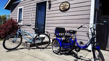Une maison à deux étages avec un vélo bleu et un tricycle garés devant.