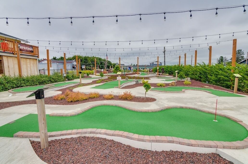A miniature golf course with a putting green, sand traps, and a wooden structure labeled 'ESPRESSO' in the background.