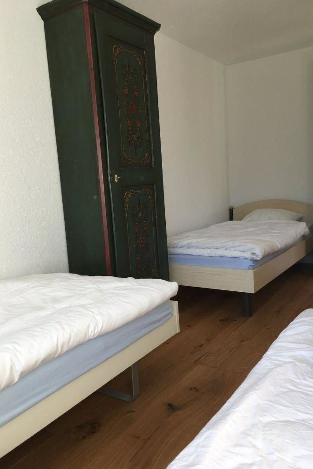 A room with two single beds and a tall wardrobe.