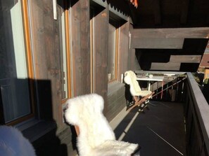 Ein Zimmer mit Holzboden, einem weißen Stuhl und einem Tisch mit Sitzgelegenheit.