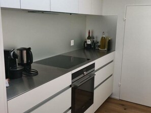 Eine Küche mit Arbeitsplatte aus Edelstahl, einer Kaffeemaschine und Weinflaschen.
