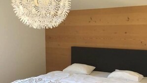 A bedroom with a bed, wooden headboard, and a hanging light fixture. - Turmalin 2. Stock Appartement/Fewo, Dusche, WC, 2 Schlafräume 5-Bettwohnung by Interhome (Lenk)