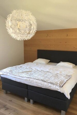 Ein Schlafzimmer mit einem Bett, einem hölzernen Kopfteil und einer Pendelleuchte.