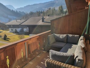 A balcony with a wicker sofa and cushions, overlooking a residential area with houses and a mountainous backdrop. - Chalet Lenk Dänk App. 6 Appartement/Fewo, Dusche oder Bad, WC, 2 Schlafräume by Interhome (Lenk)