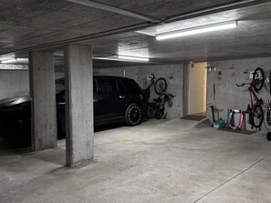 A parking garage with concrete pillars, a black SUV, and bicycles mounted on the wall. - Chalet Lenk Dänk App. 6 Appartement/Fewo, Dusche oder Bad, WC, 2 Schlafräume by Interhome (Lenk)