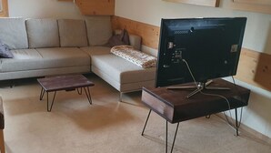 Ein Wohnzimmer mit einer Couch, einem Couchtisch und einem Fernseher auf einem Schrank.