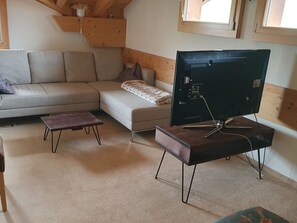 Ein Wohnzimmer mit einer Couch, einem Couchtisch und einem Fernseher auf einem Schrank.