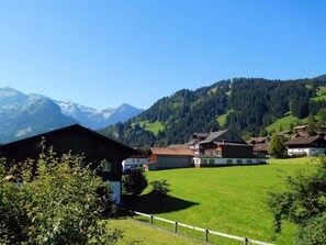 Ein ländliches Dorf mit traditionellen Häusern, einer grünen Wiese und Bergen im Hintergrund.