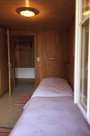 A room with a bed, a wooden ceiling, a door, and a window. - Chriba Appartement/Fewo, Dusche oder Bad, WC, 3 Schlafräume 6-Bett-Wohnung by Interhome (Lenk)