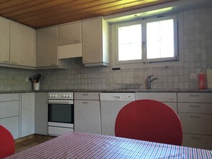 Eine Küche mit weißen Schränken, einem Fenster, einer Spüle und einem Geschirrspüler.