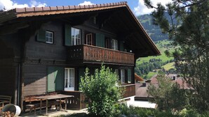 En toetages træbygning med en balkon, et træbord og en stol udenfor.