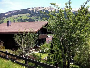 A mountain house with a red-tiled roof, surrounded by greenery and a view of snow-capped mountains. - Chriba Appartement/Fewo, Dusche oder Bad, WC, 3 Schlafräume 6-Bett-Wohnung by Interhome (Lenk)