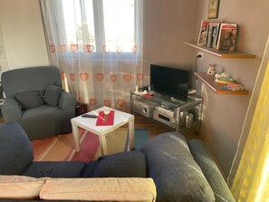 A living room with a grey sofa, a white coffee table, a flat-screen TV, and a bookshelf with books and decorative items. - SIM NOR Vacation Home… RELAX Three-Room Apartment (Budoni)