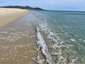 A beach with clear water, a sandy shore, and distant hills. - SIM NOR Vacation Home… RELAX Three-Room Apartment (Budoni)
